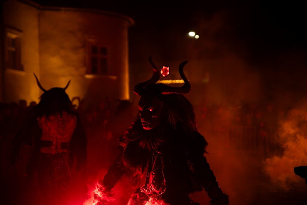 Costumed figures with horns and glowing eyes at night