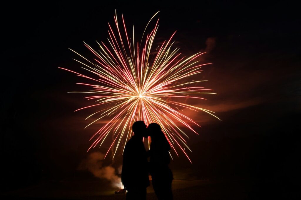 man and woman standing under fireworks during night time